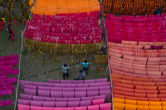 Narayanganj, Bangladesh - 08 March 2026: Aerial view of vibrant textiles laid out to dry, creating a stunning mosaic of colors under the sun, as workers tend to the fabric sheets.