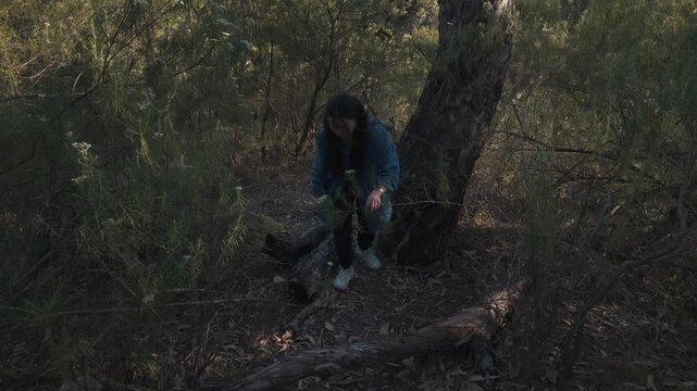 Aerial close-up of a girl trekking through Warrandyte's dense forest vegetation. The dynamic drone shot captures her cautious steps amid natural foliage, showcasing a serene outdoor adventure.