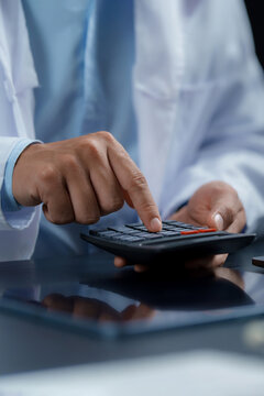 Healthcare cost management. Close-up of medical professional using calculator, representing medical expenses, hospital billing, insurance costs and healthcare financial planning. medical finance.