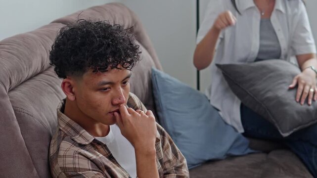 Young husband looking distressed while wife argues in background