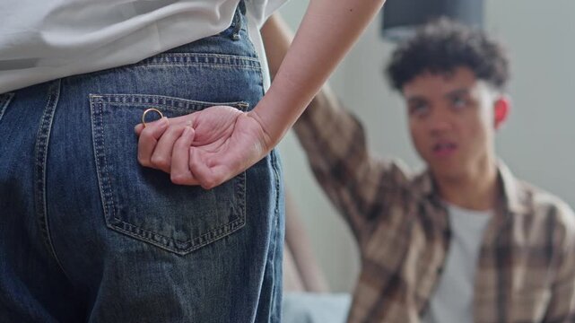 Wife hiding wedding ring in back pocket during heated argument with blurred husband
