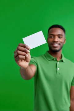 Young man holding and presenting a blank white card with space for text or graphics, isolated against a green screen