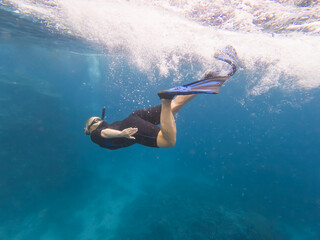 Young woman snorkeling underwater in clear blue Red Sea near White Island in Egypt wearing wetsuit and flippers during summer vacation © Dmitri