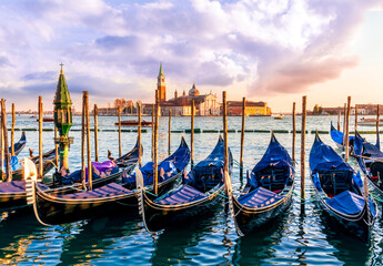 row of parked venetian gondola boats in Grand canal of Venice. Beautiful sunset or sunrise landscape with gondolas in blue water of Venice. © Yaroslav