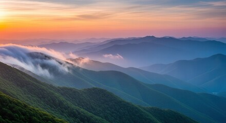 Obraz premium Sunset over rolling green mountains with misty clouds at dawn