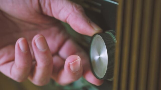 Close-up of hand adjusting tuning dial on vintage German radiogram radio player. Suitable for retro audio technology, broadcasting history and vintage media visuals.