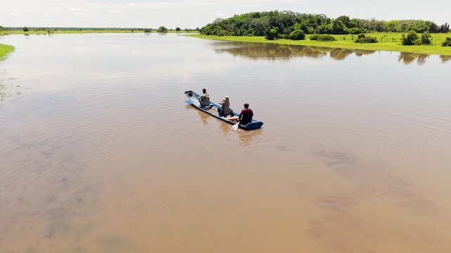 Aerial view of people navigating a traditional boat on a muddy river during a llanero safari