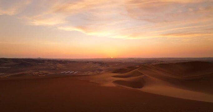 Travel couple stands on dune buggy near Huacachina in desert. Sunset aerial