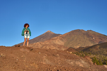 Fototapeta premium Woman photographer on volcanic ridge at sunset