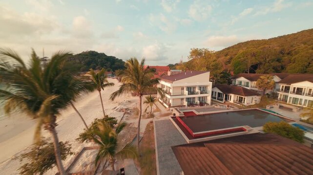 Fast cinematic FPV drone footage cruising low over the sandy coastal beach and ocean waves of Redang Island during a beautiful golden sunrise