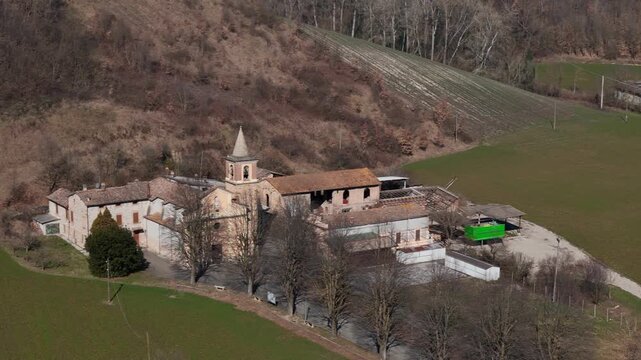 Sant Ilario Vescovo parish church and rural buildings in Chiavenna Rocchetta near Lugagnano Val d'Arda, Piacenza Province, Emilia-Romagna, Italy surrounded by farmland hills