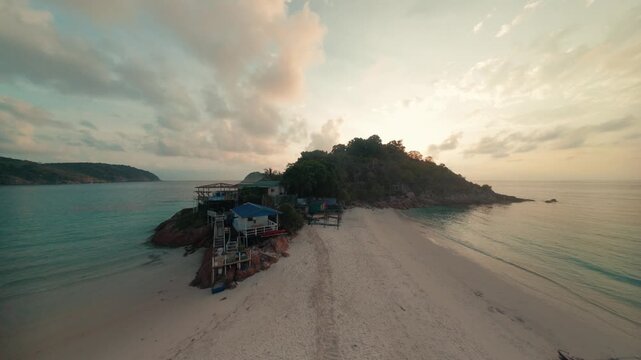 Fast cinematic FPV drone footage cruising low over the sandy coastal beach and ocean waves of Redang Island during a beautiful golden sunrise