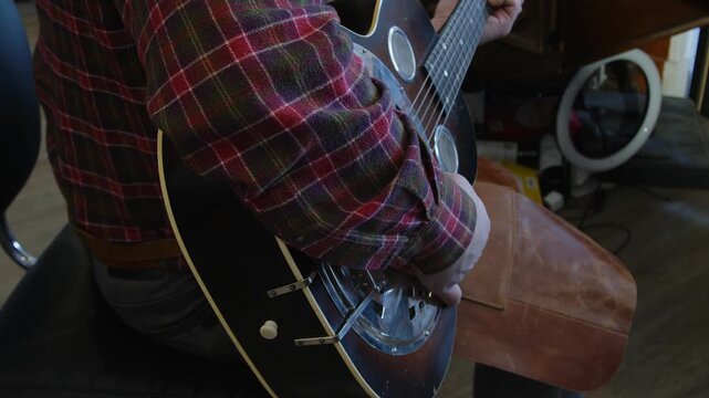 Guitar tech servicing National Steel acoustic guitar plays it in shop