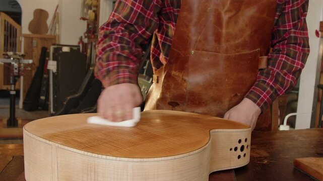 Luthier brings out bookmatched wood grain in guitar body with thin oil