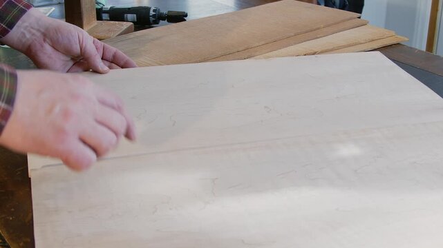 Luthier examines spruce wood blanks to build acoustic guitar in shop