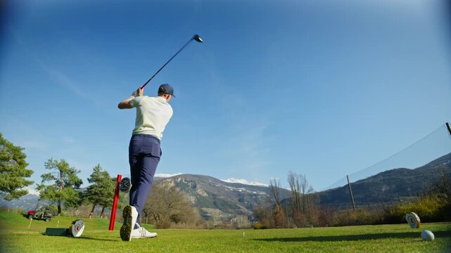 Wide angle shot of a golfer teeing off with a driver in Sion, Switzerland, with panoramic views over the surrounding Alps. Scenic golf course setting and cinematic sports moment.