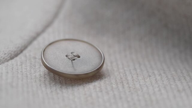 A close up view of a button on a soft white fabric, highlighting texture and detail with subtle motion