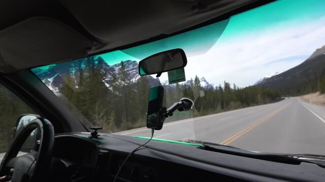 Man driving camper van on a road trip navigating through mountains and forest of the Canadian rockies