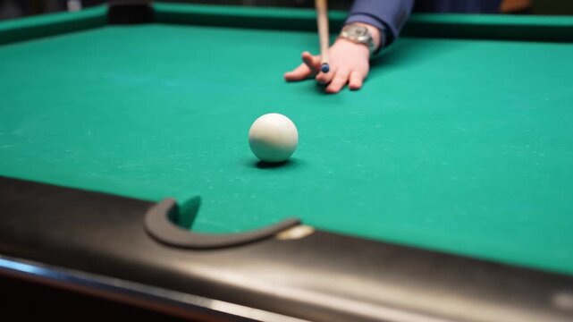 Close-up billiards shot as an orange ball drops into a pocket while the cue ball rolls nearby, shallow depth-of-field bar game footage with clean copy space.