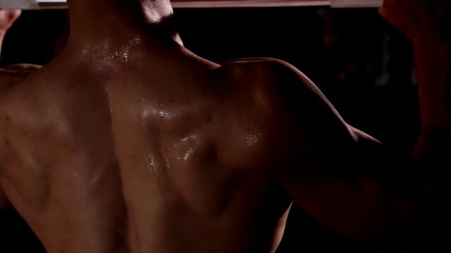 Strong muscular sportsman training biceps with six pack of abs, performing snatching heavy barbell squat, exercising lifting weights sweating profusely, showing power, strength, determination training