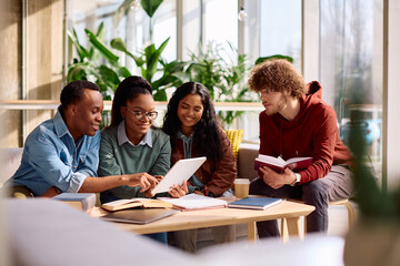 Obraz premium Happy diverse students using digital tablet while studying together at university.