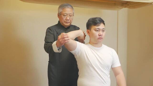 Doctor or physiotherapist orthopedic healing treatment examining treating injured arm of athlete male patient, stretching and exercise. Physical Therapy giving back massage to young man dislocations