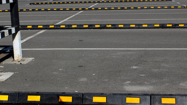 Lines Of Rubber Car Blocks And Steel Tube Fence On Open Air Parking With Road Marks
