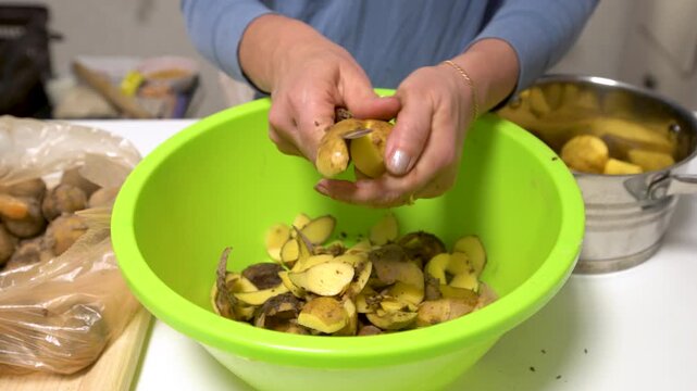 Person uses a peeler on potatoes in a green bowl on a counter, preparing food in a home kitchen for a meal.