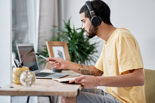 Notebook, man or headphones with laptop in home for audio transcription, editing or remote work. Freelancer, transcriber and tech at desk for playback software, recording notes and source information