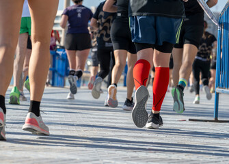 Fototapeta premium Close low angle view of marathon runners legs and shoes on waterfront race course