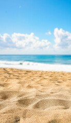 Detailed close-up of rippled golden beach sand in the foreground, contrasted with a softly blurred sea and sky background (bokeh). Peaceful coastal nature texture for copy space.