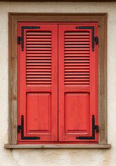 Obraz premium Red wooden shutters on a rustic window frame exterior