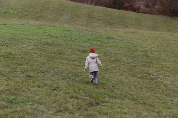 Naklejka premium Little Girl Walking Over Green Hill Childhood Exploration, Outdoor Adventure, Nature, Discovery and Healthy Lifestyle