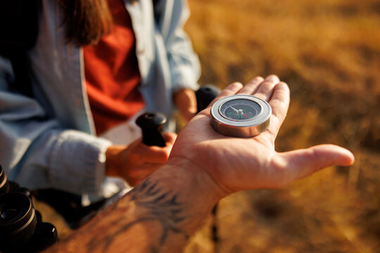 Close up detail of male hand holding compass for orientation while hiking in nature