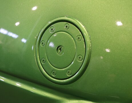Close up of a glossy metallic green custom car fuel door with keyhole lock and hex screws