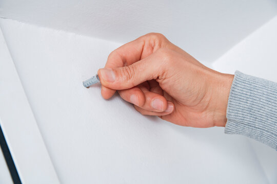 a man inserts a wall plug into a drilled hole