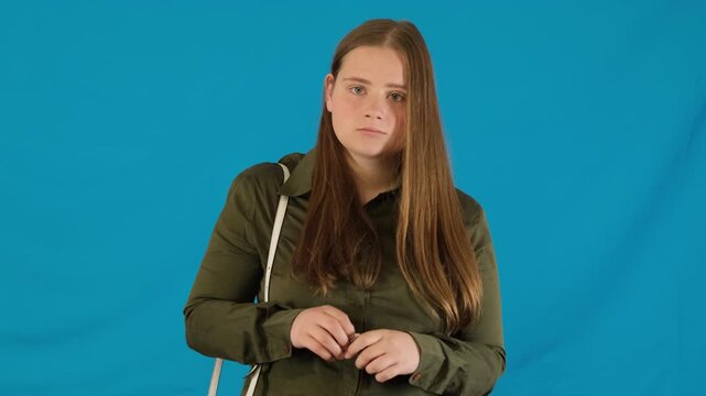 Worried young woman holds package with chewing gum on blue background. Female tries to take minty product to freshen breath before meeting