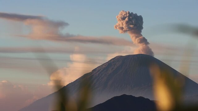 Wide shot of Sunrise Eruption of Mount Semeru Framed by Foreground Silhouettes from King Kong Hill in East Java , Indonesia