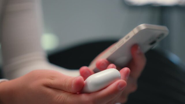 Close up unrecognizable woman holding mobile phone gadget connecting with headphones connect smartphone with wireless earphones application female girl preparing to listening music audio song indoors