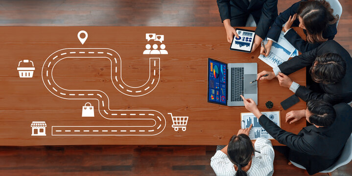 A dynamic business strategy meeting showcases a digital roadmap on a table, highlighting collaboration among professionals discussing growth and innovative ideas for development. Ledger