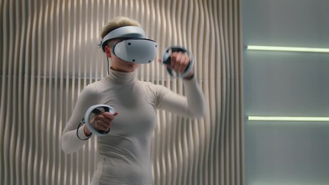 Caucasian woman holding controllers wearing vr helmet girl boxing moving hands kicking beating virtual reality futurism game in futuristic white room advanced metaverse internet online computer gaming