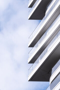Contemporary apartment building exterior showing modern architecture facade and balcony with urban sky backdrop captured in bright daylight