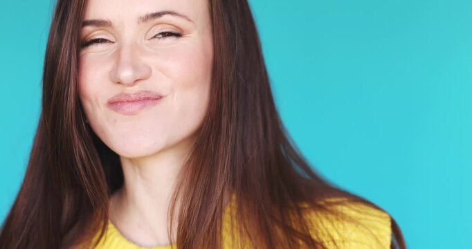 Close up portrait of a young beautiful woman eating creamy vanilla ice cream from a spoon with pleasure, happy girl tasting sweet dairy yogurt or frozen dessert on blue background, food enjoyment