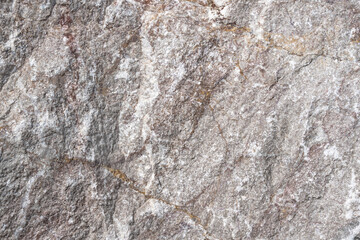 Obraz premium Close-up view of textured granite rock surface displaying natural patterns and colors, showcasing mineral deposits and geological features in a detailed manner