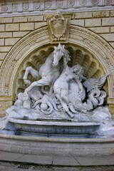Fototapeta premium A sculpture depicting a woman struggling with a horse and an octopus, set against a stone facade.
