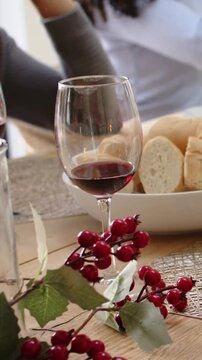 Vertical video: Moving angle bringing wine forward home table, in white reaching, in gray gesturing