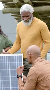 Vertical video: Holding solar panel upright, two men talking and checking on patio, mustard sweater