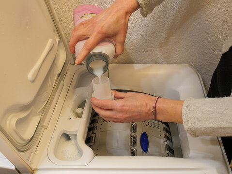 Pouring liquid detergent into washing machine compartment