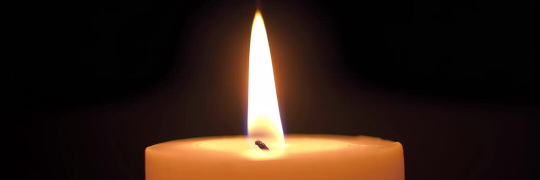 Burning candle flame on dark background with copy space, calm meditation memorial video banner background, spirituality remembrance and peaceful reflection concept.