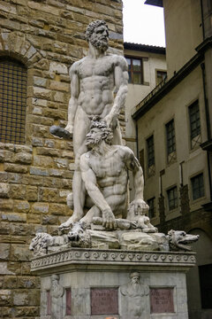 The sculpture of Hercules and Cacus stands in front of a stone building in Florence, Italy.